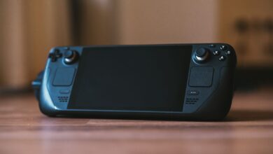 Modern handheld gaming console with buttons and joystick on a wooden surface, ideal for portable gaming enthusiasts.