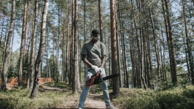 African American man operating a chainsaw in a forest setting.