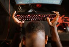 Gamer expresses frustration with video game by holding up keyboard. Overhead shot of gaming setup.