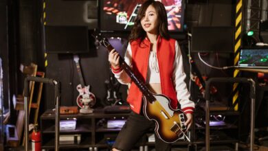 Woman playing Guitar Hero with guitar controller in a gaming room, enjoying the arcade experience.
