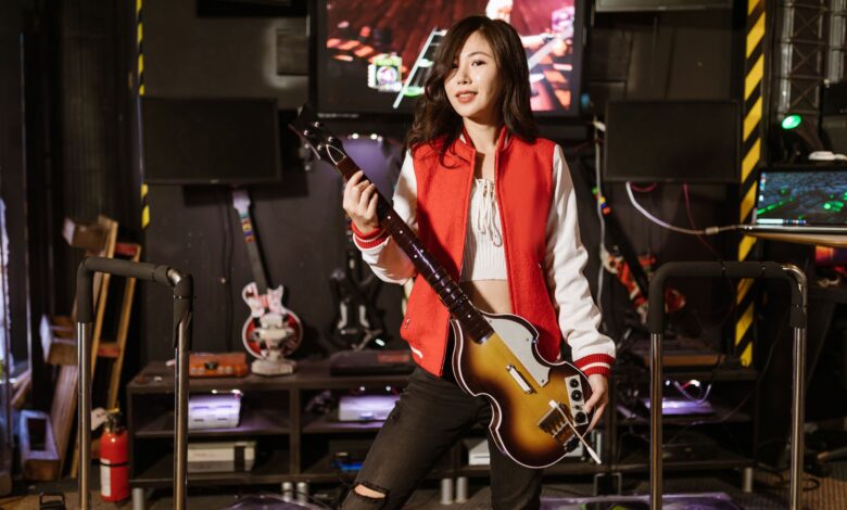 Woman playing Guitar Hero with guitar controller in a gaming room, enjoying the arcade experience.