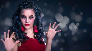 Enchanting woman with creative makeup poses in a mystical setting, perfect for Halloween themes.