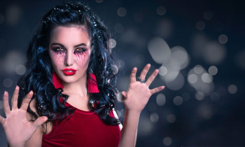 Enchanting woman with creative makeup poses in a mystical setting, perfect for Halloween themes.