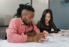 Two professionals engaged in planning during a business meeting, focusing on architectural designs.