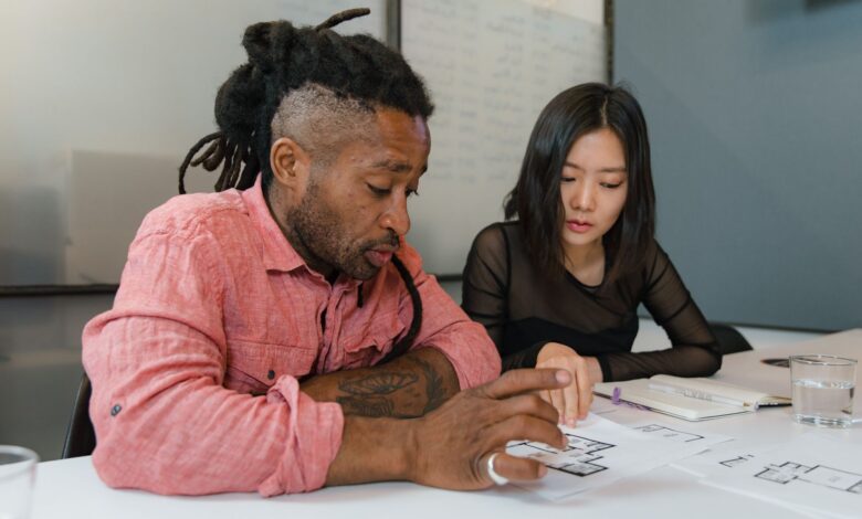 Two professionals engaged in planning during a business meeting, focusing on architectural designs.