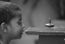 A curious child closely observes a spinning top with fascination.