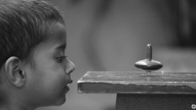 A curious child closely observes a spinning top with fascination.