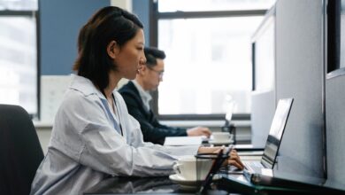 Two professionals working diligently on laptops in a modern office setup, capturing productivity and teamwork.