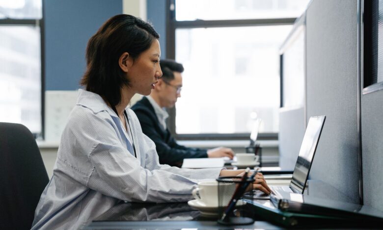 Two professionals working diligently on laptops in a modern office setup, capturing productivity and teamwork.