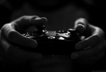 Close-up of hands holding a game controller in a monochrome setting, capturing the essence of gaming.