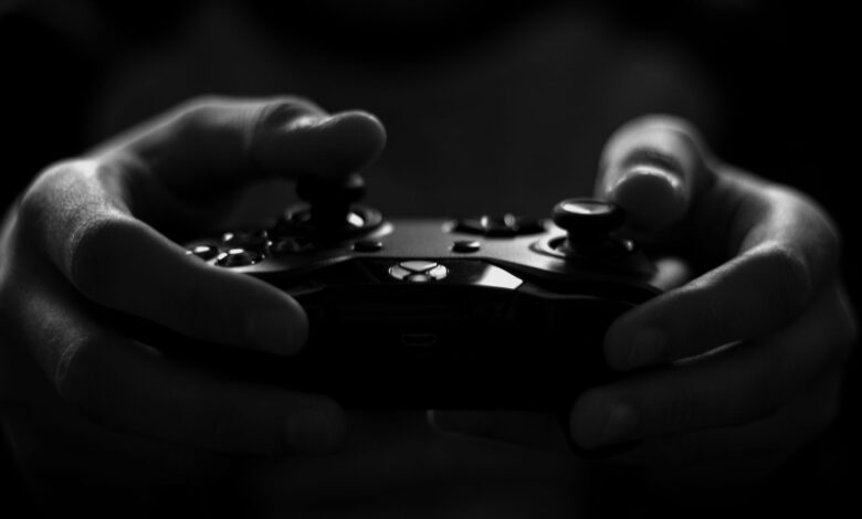 Close-up of hands holding a game controller in a monochrome setting, capturing the essence of gaming.